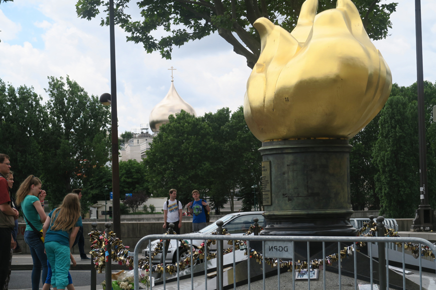 La couleur de l'or des coupoles contraste donc avec l'or traditionnellement utilisé à Paris, comme ici sur la flamme du Pont de l'Alma.